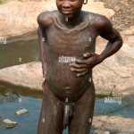 A Suri Surma naked young man body painting himself with mud Ethiopia Stock Photo