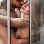 Passionate naked couple hugging and kissing while taking shower together