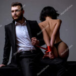 Sexy meisje naakte billen. Gepassioneerde liefhebbers. Sex overheersing. Sex inzending. Macho goed verzorgde hipster en naakte sexy vrouw vastgebonden handen rood lint. Seksuele relaties. Seks spel. Plagen en verleiden Stockfoto